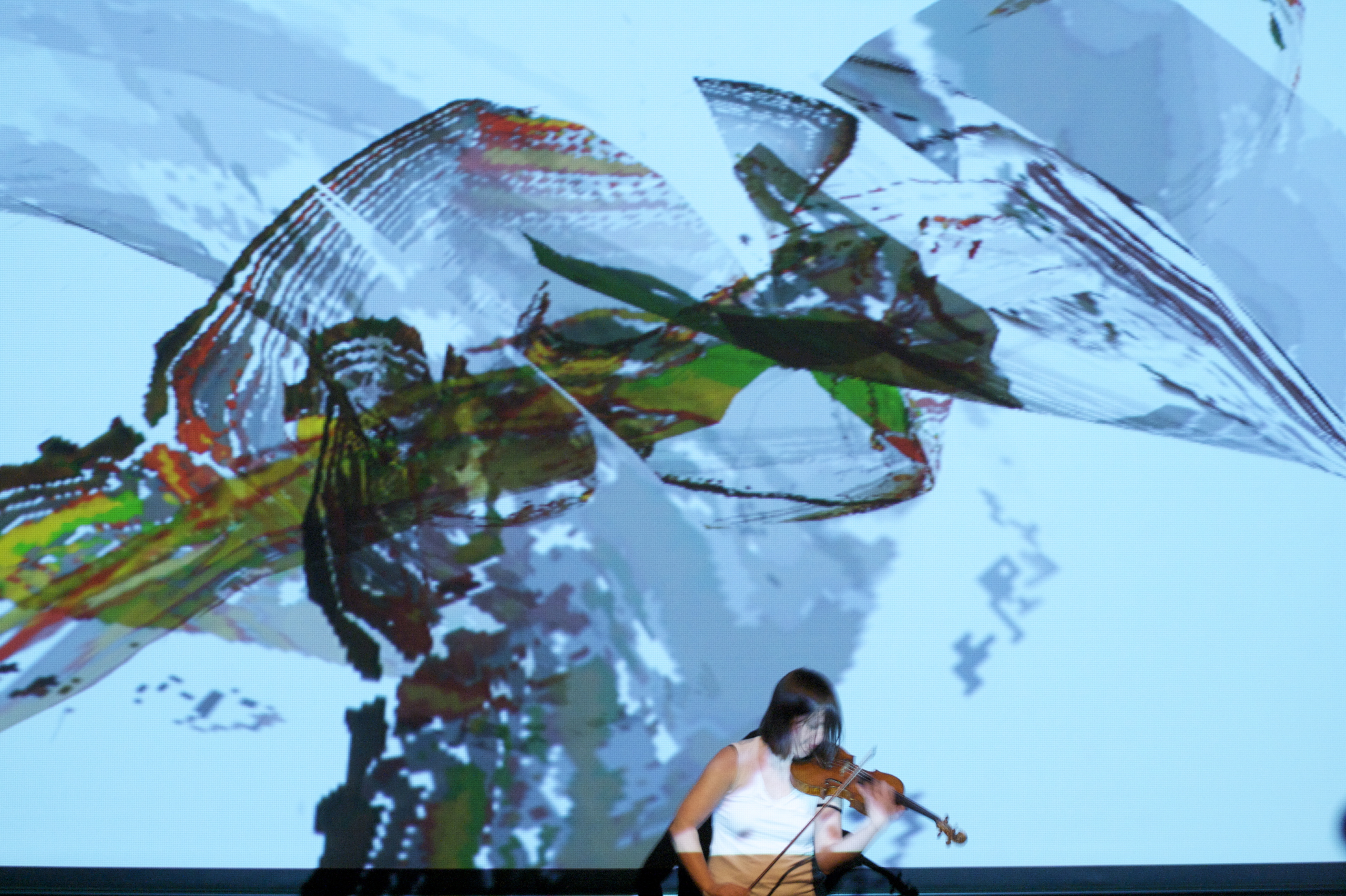 A woman plays a violin in front of an abstract, colorful digital art display.