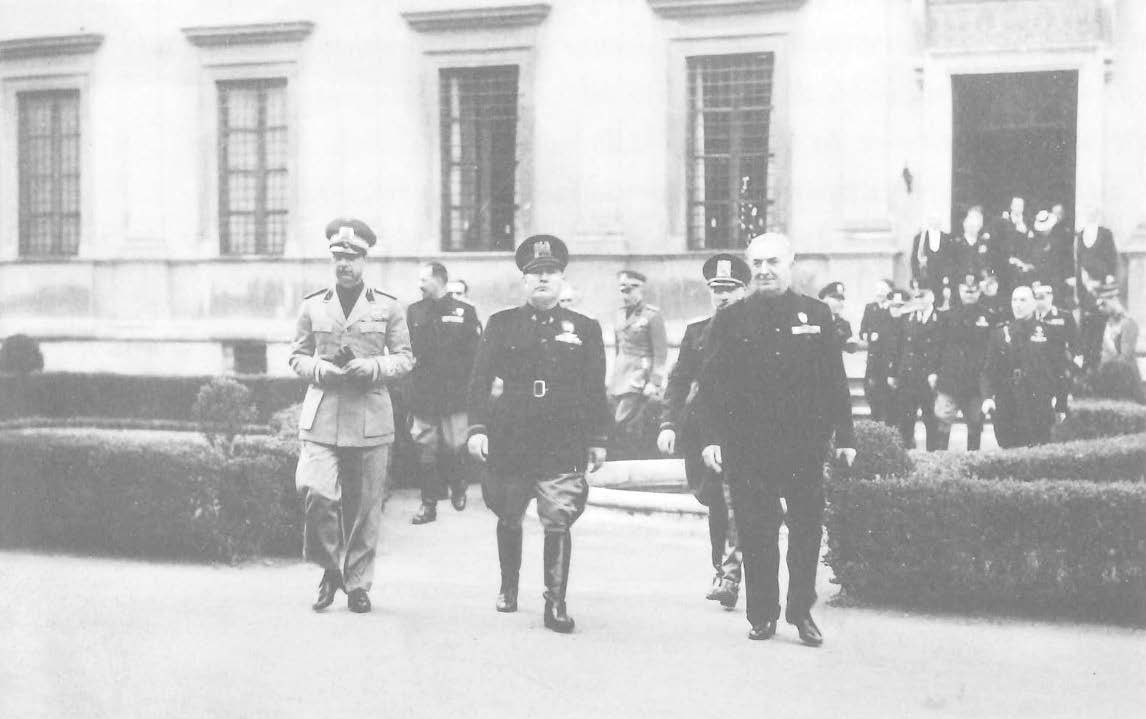 About a dozen people walking out of a building in military uniforms, three up front.