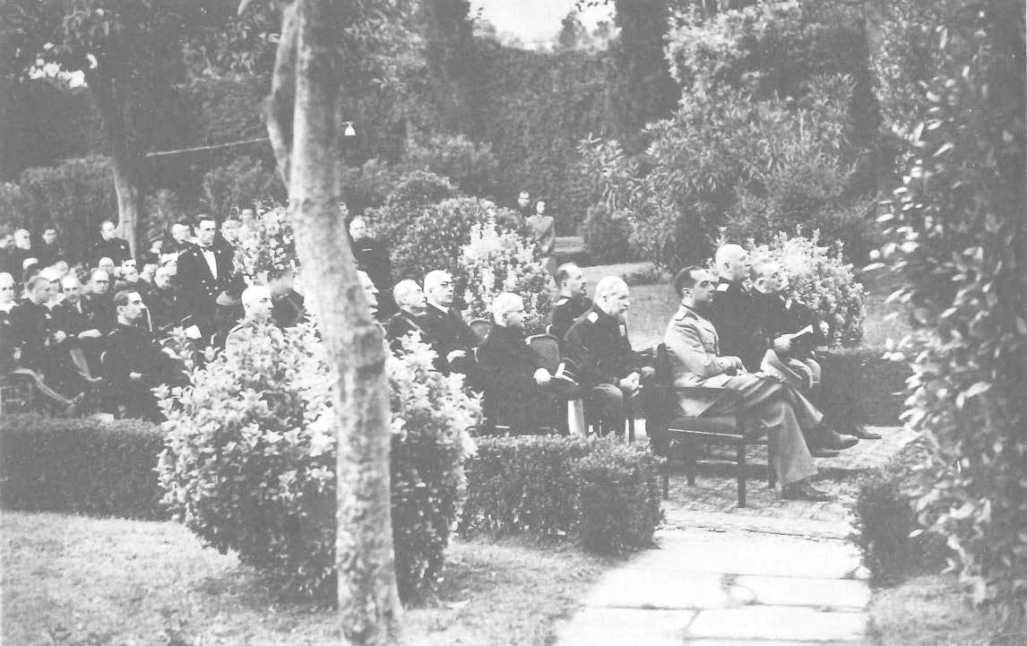 About two dozens of people sitting in a garden, directed to the right.