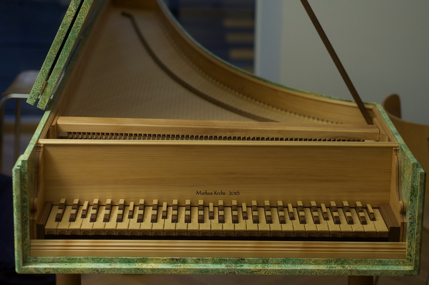 Close-up of a harpsichord-like instrument showing its wooden keyboard with multiple split keys and internal strings. The inscription “Markus Krebs · 2016” appears above the keys, indicating the maker and year.