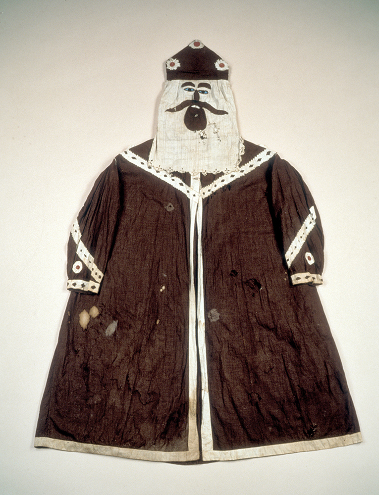 A color photo shows a dark Ku Klux Klan robe with hood and a face-like veil, reminiscent of a St. Nicholas costume.