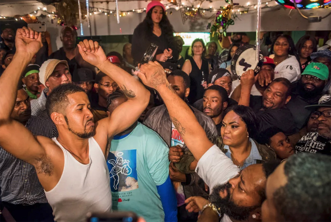 Ein Farbfoto zeigt eine Menschenmenge, die in einer überfüllten Bar zwei tanzenden Personen zusieht.