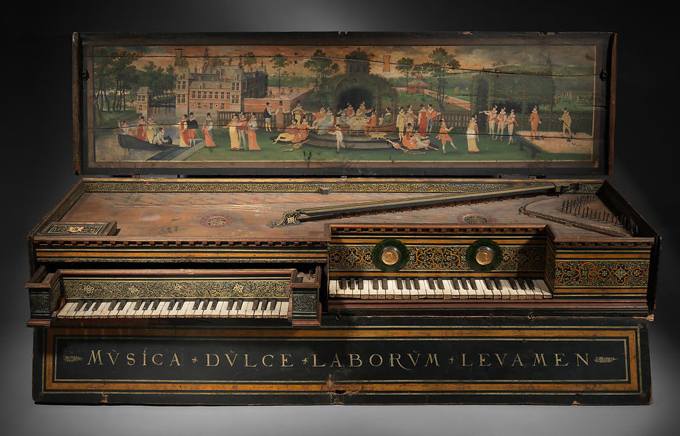 Antique double-manual virginal with richly detailed Baroque design and an open lid painted with an elegant outdoor scene. The lid artwork depicts finely dressed figures engaging in music and leisure along a riverside garden with boats, trees, and grand architecture in the background. The instrument features intricate gold and green decorative motifs around the keyboards and soundboard, with Latin text “MVSICA DVLCE LABORVM LEVAMEN” (“Music is the sweet relief of labor”) inscribed on the front panel. The instrument rests on a dark wooden base, highlighting its ornate craftsmanship and historical elegance