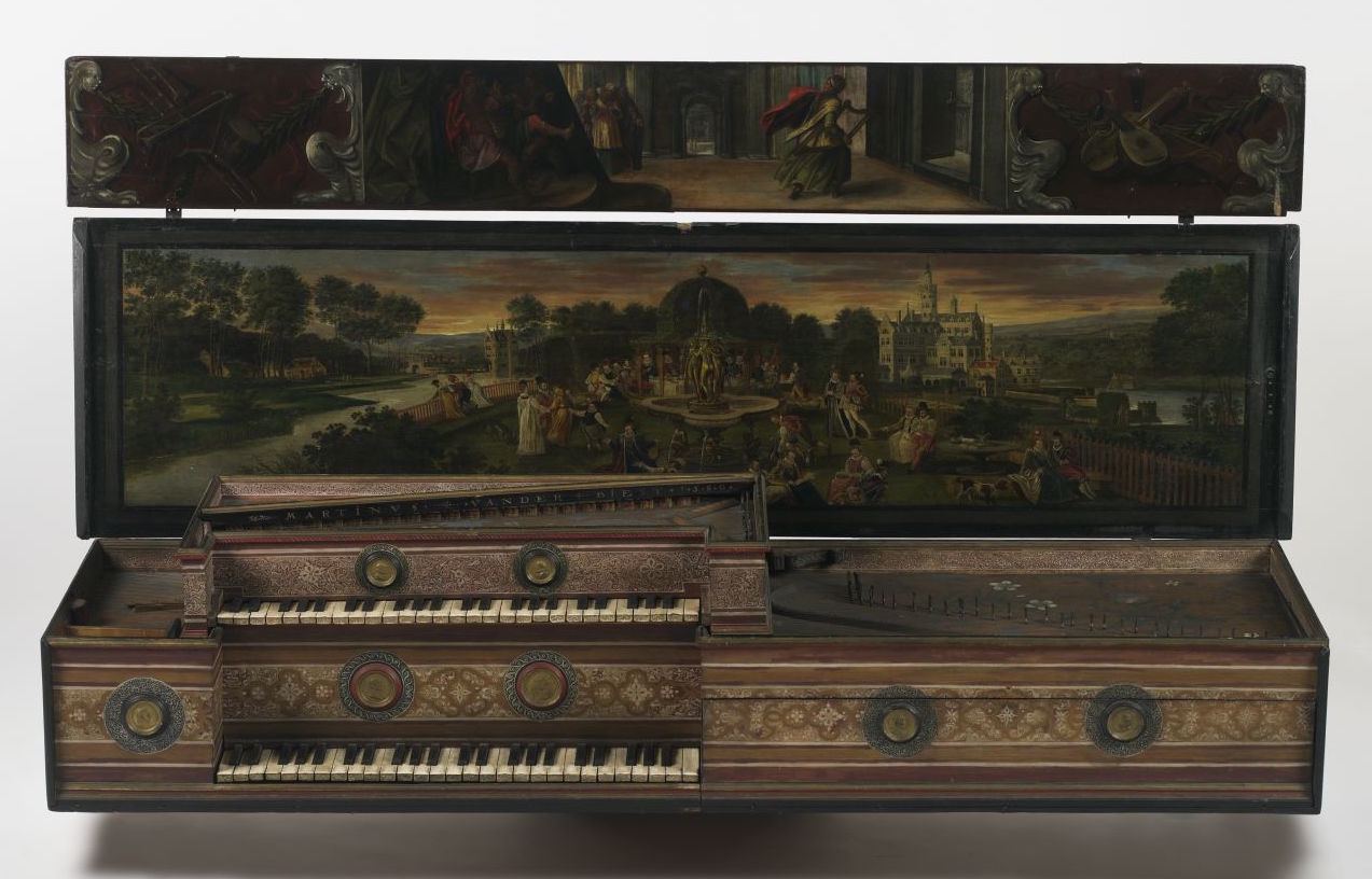 Ornate double-manual virginal with its lid open, revealing richly detailed Baroque artwork and intricate craftsmanship. The inner lid painting depicts an elegant garden scene with finely dressed figures gathered around a central fountain, set against a grand castle and sunset landscape. The upper lid shows smaller painted panels featuring musical instruments and interior scenes. The instrument itself is decorated with gilded floral motifs, circular rosettes, and patterned panels in red, gold, and cream tones. Two stacked keyboards with ivory and ebony keys emphasize its elaborate design and musical sophistication