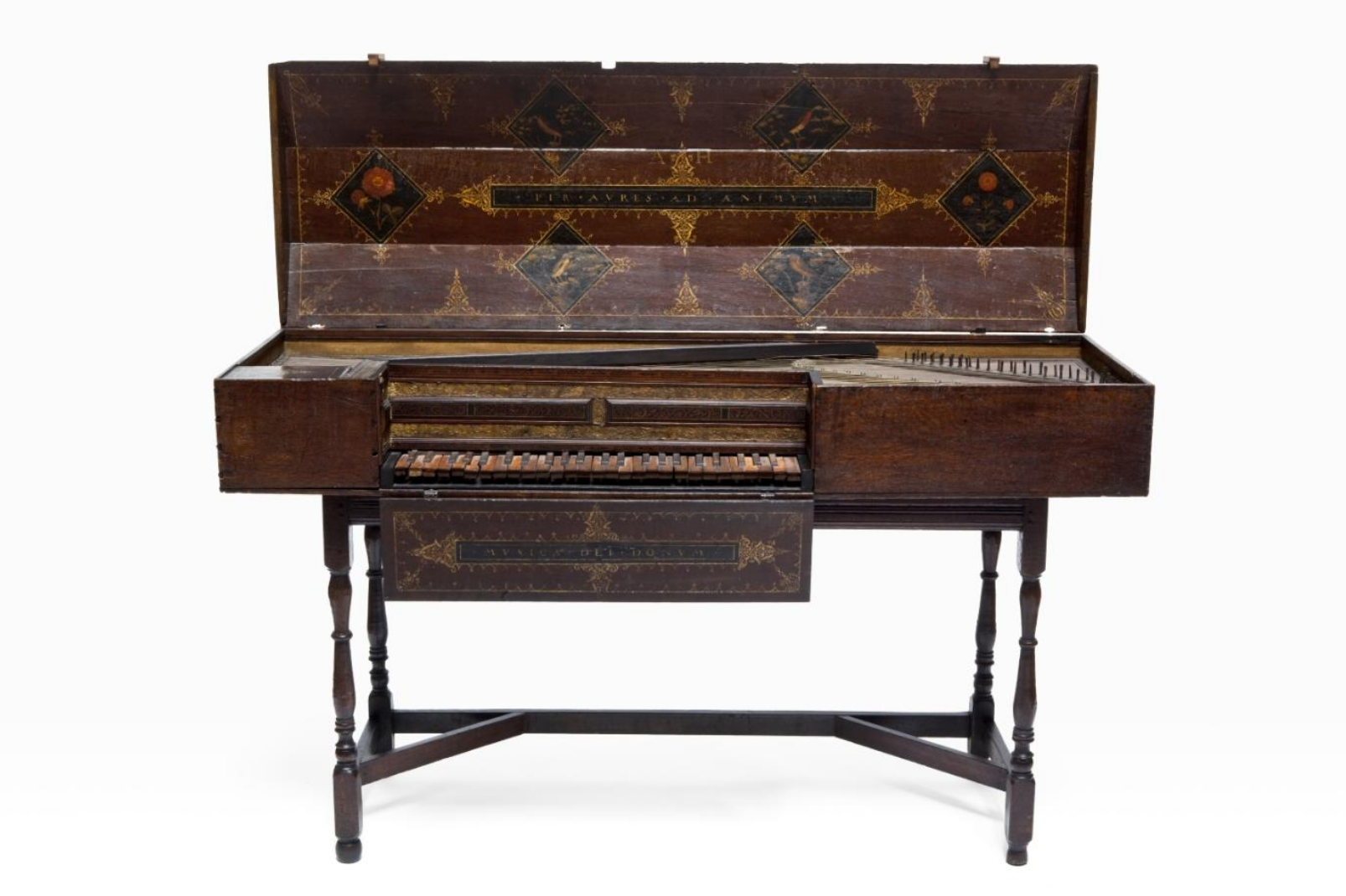 Antique Italian virginal from the 16th century, crafted in dark wood with intricate gold and painted decorations on the lid and front panels. The instrument features a rectangular case with a single manual keyboard of alternating light and dark keys, supported by four turned legs connected with stretchers. The inner lid displays ornate diamond-shaped motifs with floral and mythological designs, and Latin inscriptions in gilded lettering.