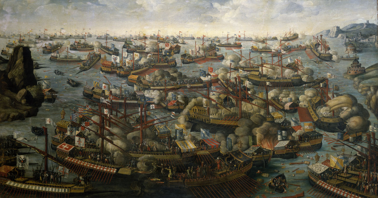 A dramatic historical painting depicting a large-scale naval battle with numerous warships engaged in combat. The scene is filled with galleys and sailing vessels adorned with colorful flags and crosses, firing cannons that create clouds of smoke across the turbulent sea. Soldiers crowd the decks, and some ships are in flames or sinking. In the background, rocky shores and distant fortresses frame the chaos of the confrontation.