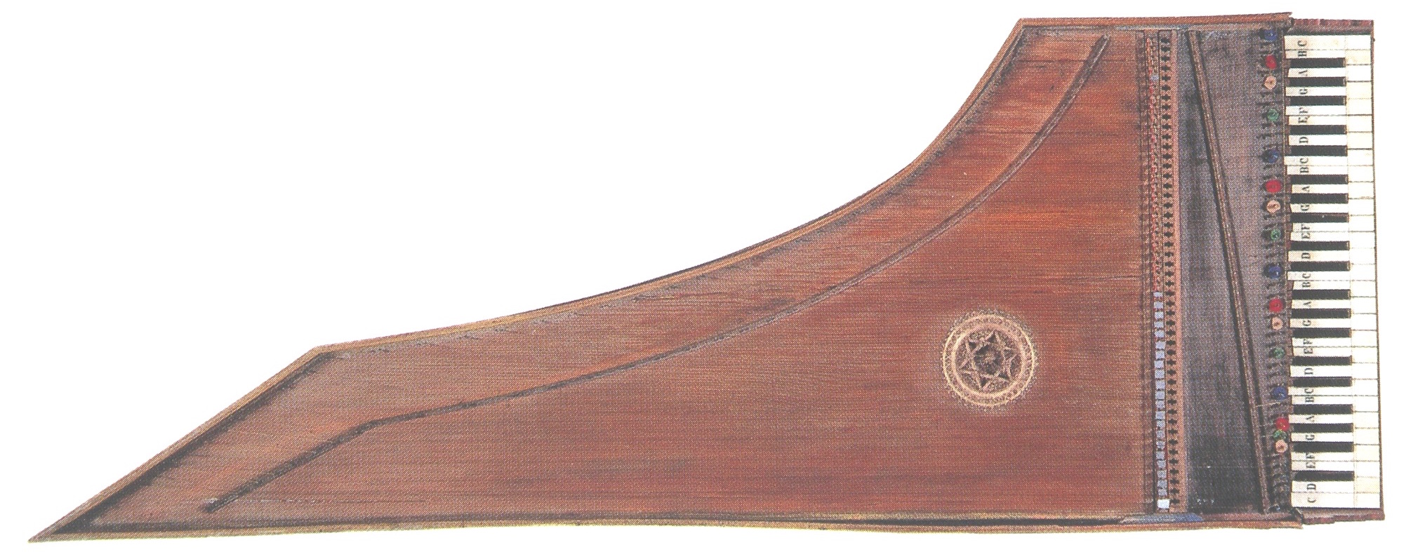 A Renaissance harpsichord, viewed from above, with a warm wooden finish. The soundboard is plain except for a decorative circular rosette featuring an intricate star-shaped design. The keyboard on the right side has alternating black and white keys, with colored markers above each note.