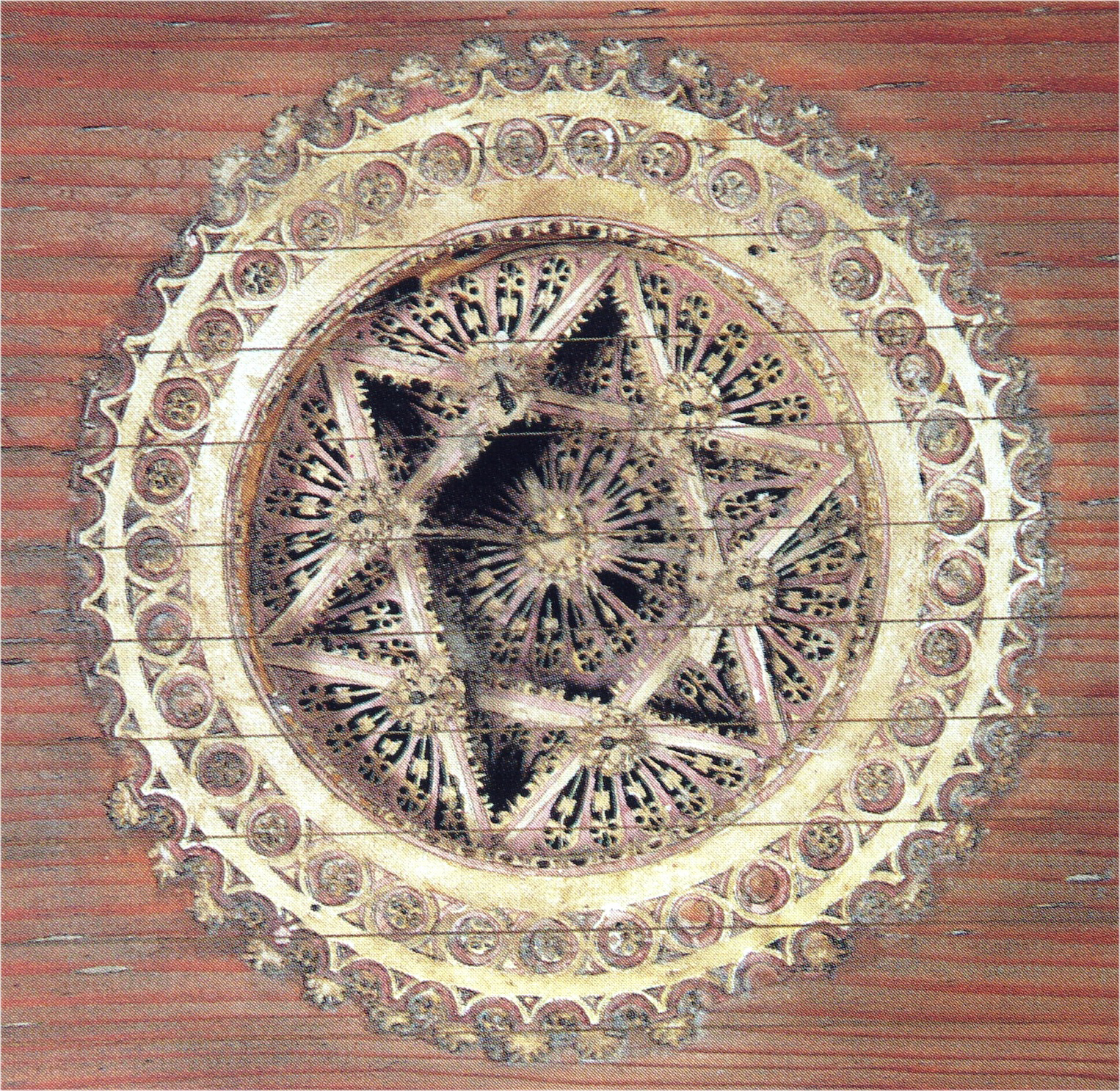 Close-up of an ornate wooden rose from a Renaissance harpsichord, intricately carved with interlaced geometric and floral motifs. The circular design features a six-pointed star at its center surrounded by delicate latticework and concentric decorative rings, each adorned with small, repeating patterns. The craftsmanship showcases meticulous detail and symmetry