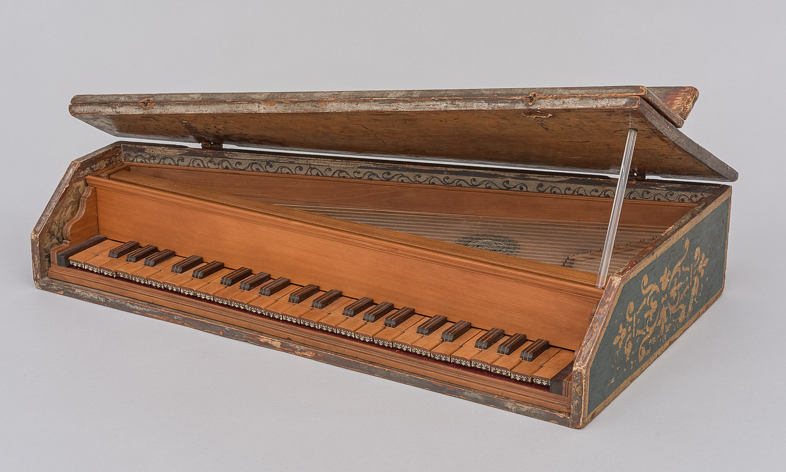 A small Italian spinettino from the second half of the 16th century, housed at the Kunsthistorisches Museum in Vienna. The instrument features a slanted rectangular shape with a hinged lid, a single manual keyboard with dark accidentals, and delicate painted decorations on the case. The strings and soundboard are visible under the open lid, showcasing fine Renaissance craftsmanship.
