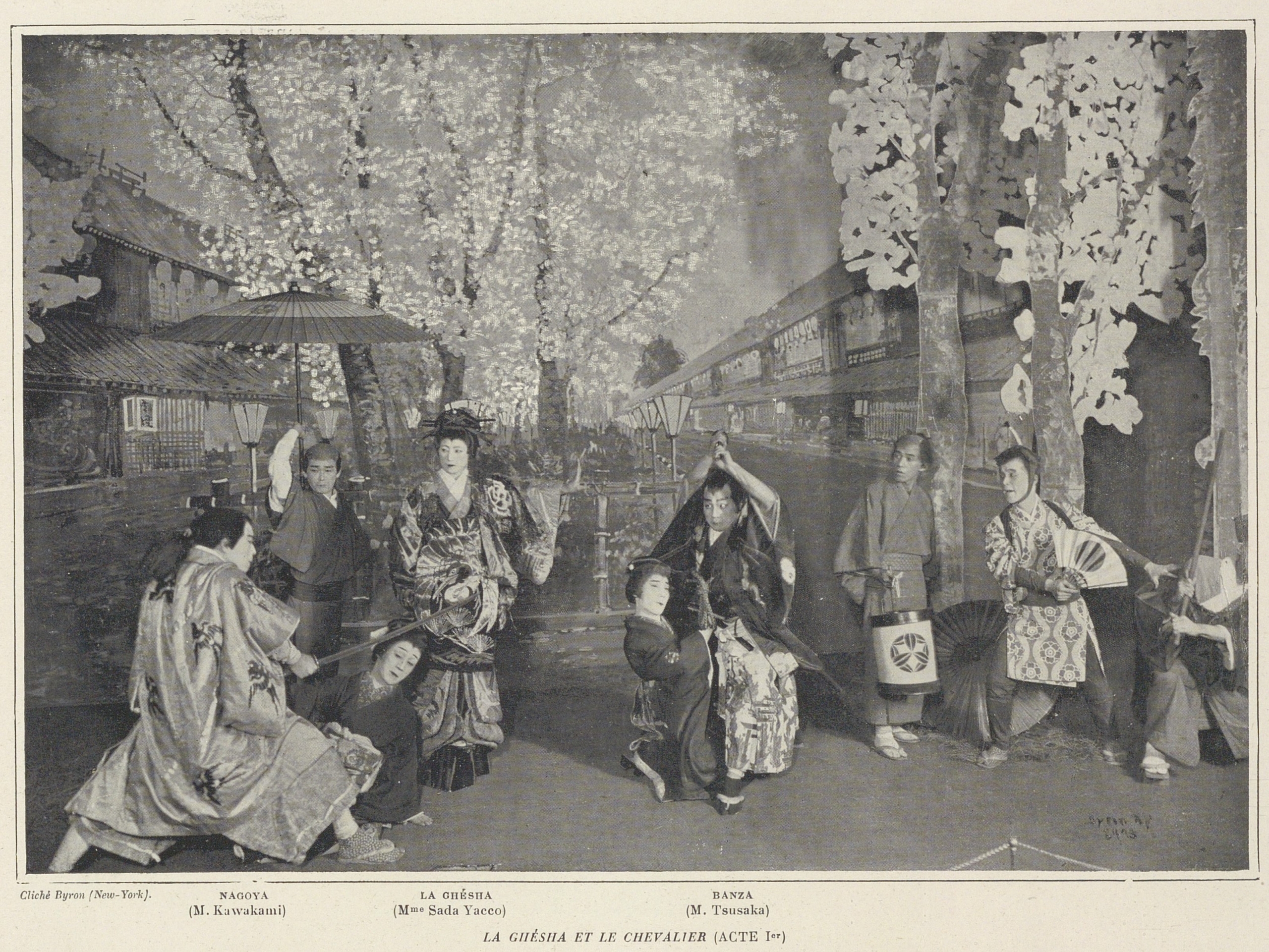 A black and white photo-engraving, likely from a European magazine, showing a scene from a Japanese theatrical production, titled "LA GHÉSHA ET LE CHEVALIER (ACTE Iᵉʳ)" [The Geisha and the Knight (Act 1)]. The actors are in full costume on a stage set designed to look like a street or garden lined with cherry trees in full bloom (sakura). The scene depicts dramatic action: a figure (labeled "La Ghésha" - Mme Sada Yacco) in a kimono stands centrally, while figures around her, including some in traditional Japanese dress (labeled "Nagoya," "Banza," etc.), crouch, kneel, and posture with hands raised as if in combat or intense emotion. A parasol and sword props are visible. Captions identify the actors and roles.