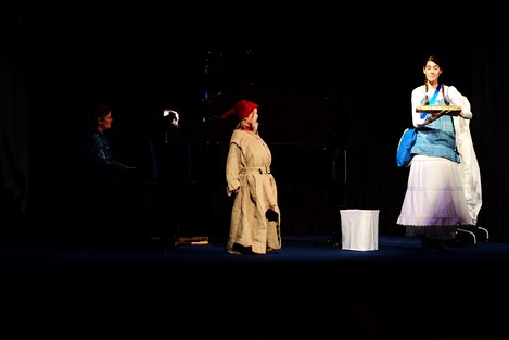 Bühnenbild: Agathe spielt auf einem Glockenspiel, ein Kind mit Zwergenmütze schaut sie an