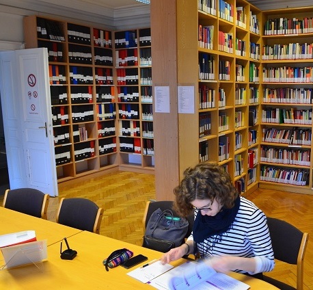Studentin sitzt mit aufgeschlagenem Buch in der IMP-Bibliothek