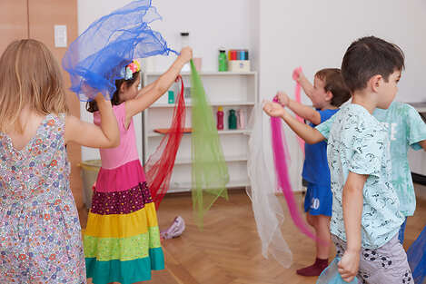 Stehende Kinder die mit bunten Seidentüchern tanzen. 