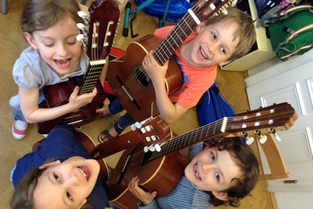 Vier Kinder stehen im Kreis und jedes hat eine Gitarre in der Hand
