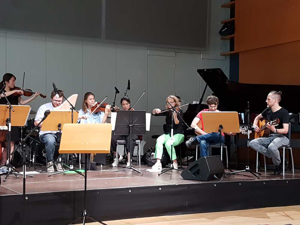 Foto von acht Musikern auf der Bühne des Festsaals