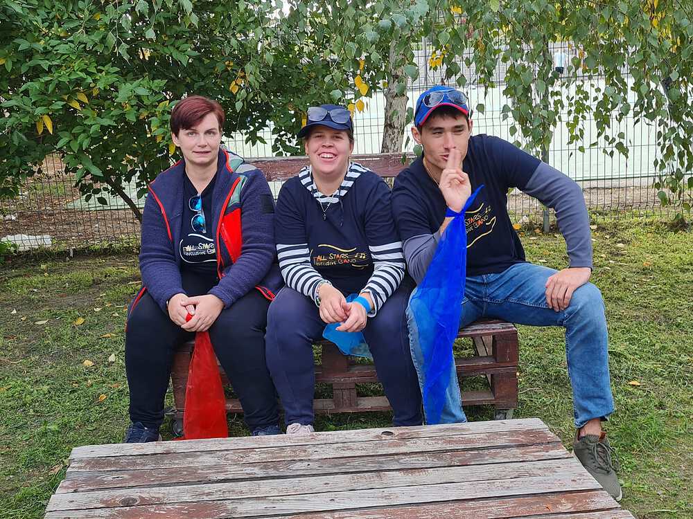 Foto von 3 Mitgliedern der All Stars Inclusive  Band die auf einer Bank im Freien sitzen